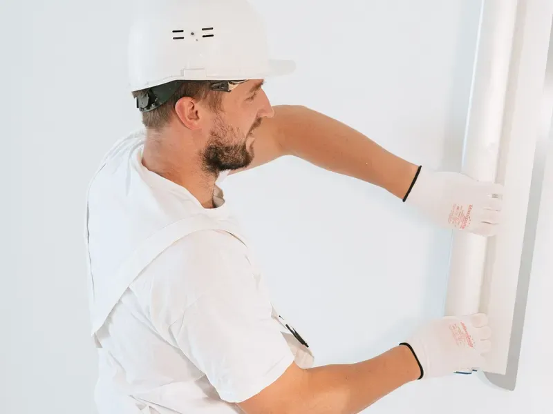 Worker in a hard hat installing a drywall panel
