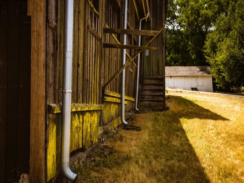 Rain gutters and downspouts along the eave of a wooden barn