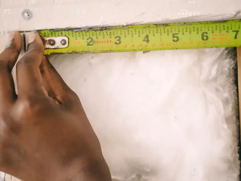 Measuring tape laid across fiberglass insulation for a cut