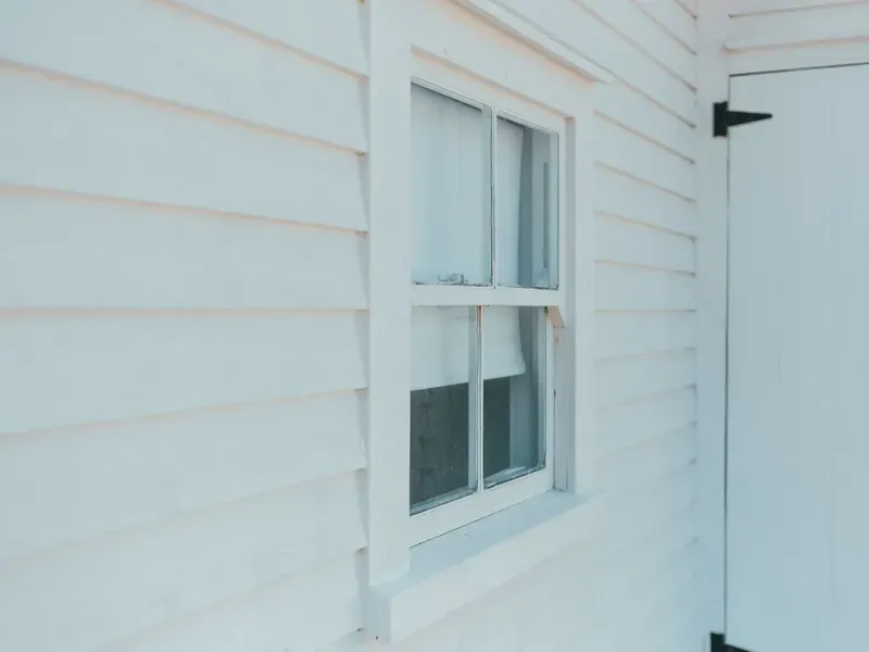 Close-up of a window on a white lap-siding house exterior