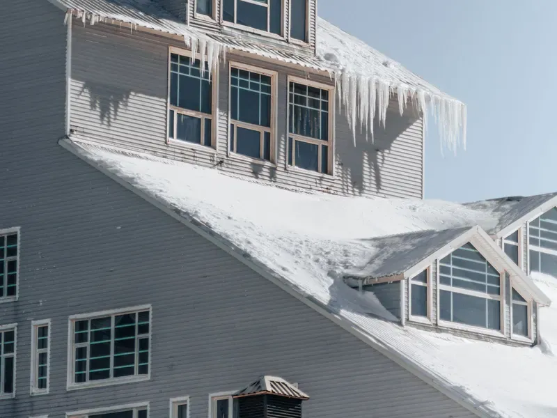 Icicles hanging from the snow-covered roof of a house in winter